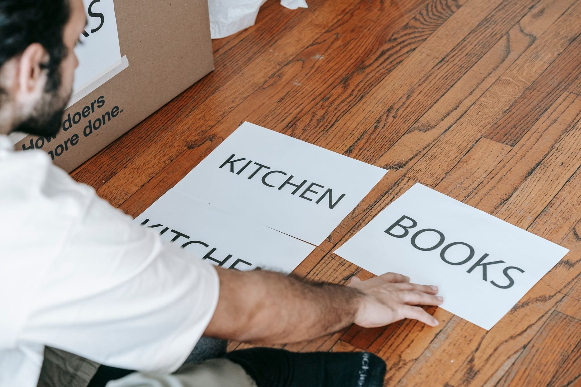 A man sorts and labels household items during a home moving process indoors